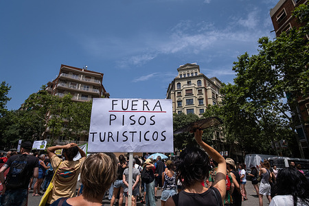 A protestor holds a placard expressing their opinion against tourist apartments during a demonstration. More than a thousand protesters marched through the center of Barcelona to the Sagrada Família basilica against the touristification of Barcelona, ​​which is creating precarious employment in the service sector and increasing housing prices.