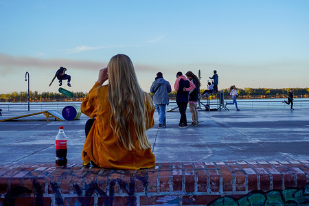 A young woman watches skateboarders on Rosario's promenade overlooking the Parana River, while smoke from wetland fires can be seen in the distance. Wetlands are being traditionally burnt for use in agriculture, but over the last years fires went completely out of proportion, threatening a varied, fragile and important ecosystem.