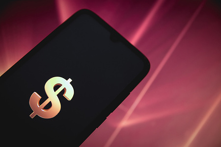 In this photo illustration, a Dollar $ logo seen displayed on a smartphone screen with a computer wallpaper in the background.