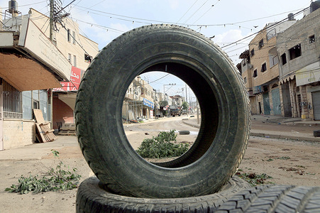 Military vehicles seen through a tire in the middle of the market during a large-scale military operation in the town of Qabatiya, south of Jenin in the northern West Bank. The Israeli army imposed a curfew on residents, the army raided and searched Palestinian homes for Palestinian militants and military equipment. This followed a Palestinian attack that killed an Israeli man and woman in the southern Israeli city of Beit She'an. The Israeli Defense Minister ordered the army to tighten the siege and close markets, shops, and roads leading to Qabatiya.