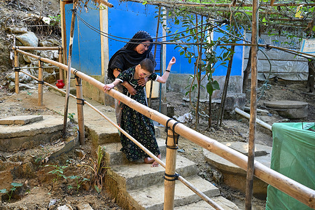 With the support of her mother and using a bamboo handrail, Noor Kolima (17-years old), a special child, makes her way from the toilet to the shelter. Bangladesh is home to the world’s largest refugee settlement, where around one million Rohingya refugees live in the camps of Cox’s Bazar. Most fled Rakhine State, Myanmar, during the mass violence of 2017, joining earlier waves of displacement that began decades ago. Amid overcrowded shelters, limited mobility, and prolonged statelessness, the Rohingya have built vibrant community spaces, preserved cultural traditions, and adapted to a challenging environment. They continue to study, work, play, and celebrate life, demonstrating resilience, agency, and creativity in the face of adversity.
