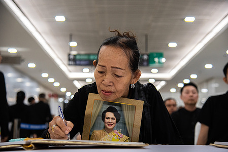 A mourner holds a portrait of Queen Mother Sirikit while signs books of condolences during the mourning ceremony for Queen Mother Sirikit at Chulalongkorn hospital. The Queen Mother Sirikit died at the age of 93 years old on 24 October 2025 at the Chulalongkorn Hospital.