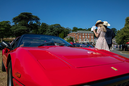 A man and women walk behind a classic red Ferrari. The Royal Automobile Club (RAC) hosted its inaugural Concours at the Woodcote Park Estate. The event showcased more than fifty vehicles representing over a century of motoring history, including veteran, vintage, classic, racing automobiles, and motorcycles. Displays were positioned throughout the club’s grounds and in designated exhibit areas. All participants were judged by a panel of industry experts and notable personalities, with awards being presented later that day.