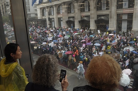 People view through a window anti-Trump demonstrators marching on the street. Demonstrators in Manhattan protested against Donald Trump on his birthday in a “No Kings” rally. Protesters claimed Trump is acting as if he has ultimate power and challenging the government’s checks and balances system. Demonstrators condemned Trump’s immigration policies and the U.S. Immigration and Customs Enforcement or ICE for arresting and deporting immigrants. The protest comes amid protests in Los Angeles and in cities nationwide opposing ICE immigration raids.
