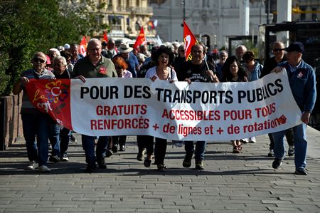 Protesters hold a banner and flags marching along Marseille's Old Port while chanting slogans during the demonstration. Following the announcement by Nicolas Isnard, President of the Aix-Marseille-Provence Metropolis to end all free public transport, demonstrators marched from Place du Général de Gaulle to Marseille City Hall.