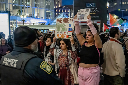 Protesters hold up placards expressing their opinions while blocking the entrance to Boston's busiest train station during a demonstration. Pro-Palestine groups around the US gathered at the South Station in Boston during the second day of their protest. They made a series of actions to halt business and to hear their call for a ceasefire in the Israel-Hamas war.