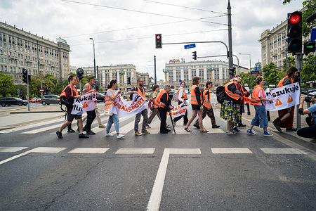 Climate activists peacefully leave the road after the temporary blockade comes to an end during the demonstration. Climate activists from the Last Generation (PL: Ostatnie Pokolenie) group block roads around Warsaw. One of four groups working concurrently, these activists blocked roads in the city centre and on bridges across the Vistula River. At midday, all four groups come together for one final blockade. Unlike other protests where the activists have glued themselves to the roads, the activists block the road only for 1 or 2 cycles of the pedestrian traffic crossing lights. The action is in answer to a cancelled appointment to meet Warsaw's mayor and failed presidential candidate, Rafal Trzaskowski. The climate activists direct their demands to Trzaskowski, namely to redirect funding for new motorways to public transport, and to introduce a public transport ticket for all priced 13.42 United States Dollar per month.