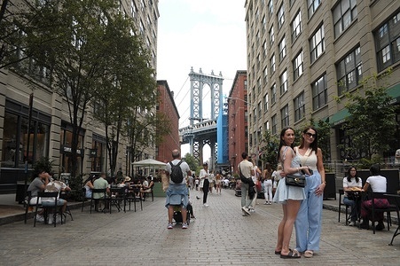 A couple pose for a photo in Dumbo in front of a view of the Manhattan Bridge in Brooklyn, New York City.