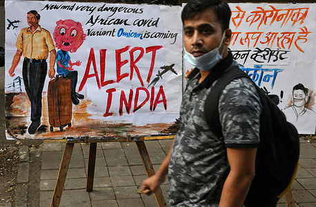 A man wearing a protective face mask lowered to her chin walks past a painting made by Gurukul school of art to create awareness about the new variant of coronavirus which has emerged in South Africa.
Brihanmumbai Municipal Corporation (BMC) as a precautionary measure will quarantine South Africa returnees on arrival in Mumbai.
