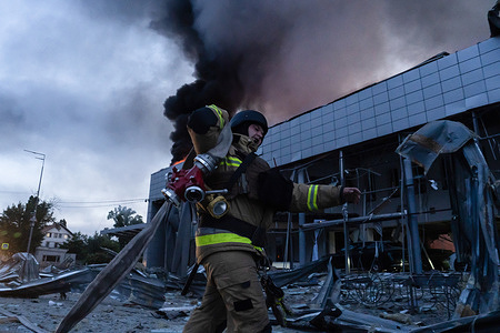Ukrainian firefighter works to extinguish a burning commercial building damaged during a Russian missile and drone attack in Kyiv.
