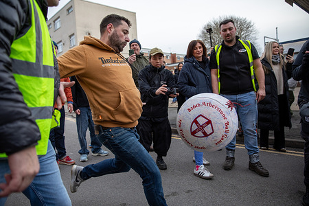 A competitor taking part in the 826th Atherstone Shrove Tuesday Ball game kicks the match ball to re-start the game. Hundreds compete in the 826th Shrove Tuesday Ball Game held in the English market town of Atherstone. Dating back to the 12th century, two teams made up of men from Warwickshire and Leicestershire, fight grapple and scrum to keep possession of an oversized leather ball for two hours. Starting at 3pm on Shrove Tuesday competitors follow two rules; “stay on the high street” and “don’t kill anyone.” Victory goes to the team holding the ball at 5pm or when the final klaxon sounds.
