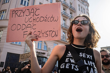 An activist holds a placard, written in Polish, that says "Accepting refugees, giving back fascists". On the afternoon of International Women's Day, the 8th of March, Varsovians march through the streets of Warsaw for the 27th annual Manifa, an annual feminist street demonstration. Under the slogan "Solidarity in Times of Capitalypse", activists march with placards and banners from Unii Lubielski Square through the centre of Warsaw, to the Charles De Gaulle roundabout, where DJs provide music for a street party.