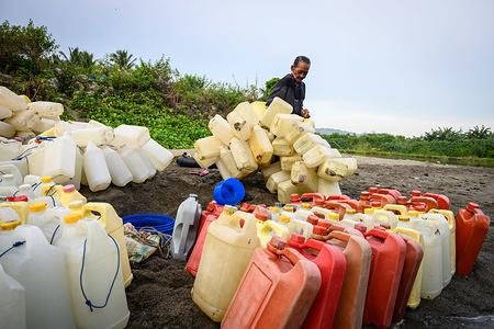 Ma Sappe (78) seen with her jerry cans at the river banks.
A number of women travel every day for around 4 km to get to Tinambung River where they swim with hundreds of jerry cans to get clean water. A jerry can is sold for Rp. 500 ($ 3.5 cents) to meet their needs. West Sulawesi, Indonesia.
