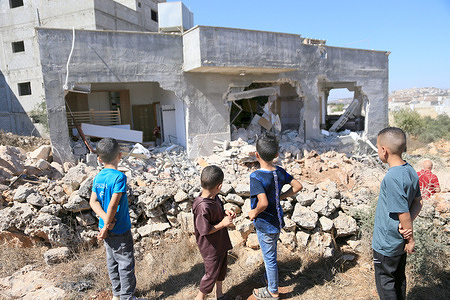 Palestinian children look at a damaged house after it was demolished by the Israeli army during a military operation in the village of Aqraba. The Israeli army announced that it killed a young Palestinian man after he barricaded himself inside the house, the Israeli soldiers shot him before their bulldozers demolished the house on top of him.