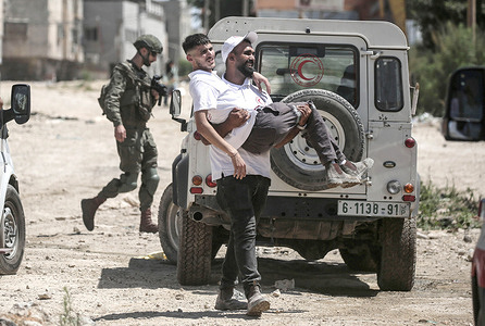 A Palestinian paramedic carries an injured person during the displacement of Palestinian families in the Tulkarm refugee camp. Israeli forces allowed residents to retrieve their belongings after issuing demolition notices for several homes, amid a months-long offensive in the West Bank that has displaced some 35,000 Palestinians from their homes in the Tulkarm refugee camp.