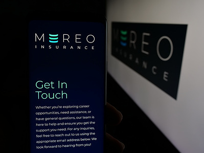 In this photo illustration, a person is holding a cellphone with the webpage of financial company Mereo Insurance Limited on screen in front of logo.