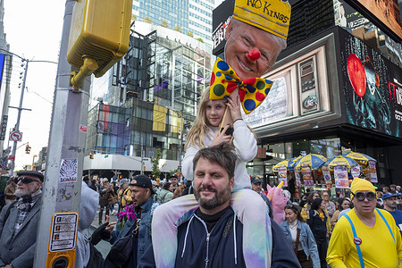 A girl seats on her fathers shoulders holding a placard participates in a "No Kings" protest in Manhattan. Organizers expect millions to participate in cities and towns across the nation for the second "No Kings" protest to denounce the Trump administration.