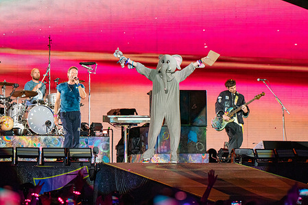 The band Coldplay are seen on stage with a member of the audience dressed in an elephant costume at Wembley stadium. Coldplay played the first night of their 10 date run at Wembley Stadium London UK as part of their record breaking Music of The Spheres World Tour.
