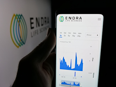 In this photo illustration, a person is holding a smartphone with the web page of ultrasound company ENDRA Life Sciences Inc. on screen in front of logo.