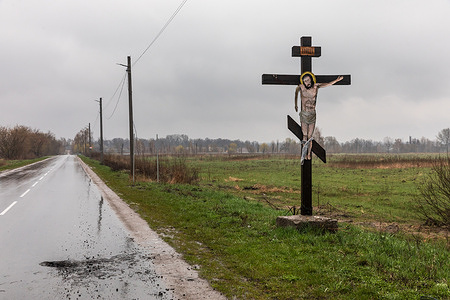A crucifix with a statue of Christ by the side of the road damaged during fighting between Ukrainian and Russian forces. Russia invaded Ukraine on 24 February 2022, triggering the largest military attack in Europe since World War II.