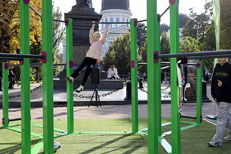 A girl exercises on horizontal bars in Cathedral Square. The social project of the Ukrainian President and the Ministry of Youth and Sports, “Active Parks: Locations of a Healthy Ukraine,” aims to create a navigation map for outdoor recreation in parks and squares. The initiative promotes systematic training sessions designed to develop core strength, agility, coordination, flexibility, and overall fitness.