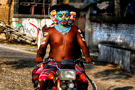Hindu devotees seen riding on a motorbike with their colorful faces before taking part in the annual Gajan Festival in a remote village of West Bengal. Gajan is a Hindu festival celebrated mostly in the rural part of West Bengal. Gajan spans around a week, starting mid-April. Participants of this festival are known as Sannyasi or Devotees. The central theme of this festival is deriving satisfaction through non-sexual pain, devotion, and sacrifice.