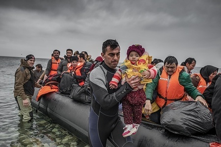 A volunteer seen helping a child to get off the boat as it arrives in Greek soil from Turkey.
In 2015 and 2016, tens of thousands of refugees from the middle east escaping war from their home countries arrived on the shores of the Greek island of Lesbos after crossing the Aegean Sea from Turkey. Hundreds of people drowned while attempting to cross this sea.