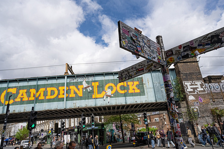 The iconic Camden Lock bridge seen over Camden High Street, a busy market popular with street food stalls and alternative shops catering for music and fashion culture.