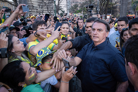 Brazilian president Jair Bolsonaro (R) greets supporters with mobile phones taking selfies of the candidate during a campaign rally at Praça da Liberdade in Belo Horizonte in Minas Gerais State.