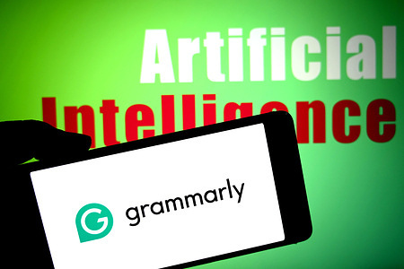 In this photo illustration, a Grammarly logo is seen displayed on a smartphone with the words 'Artificial Intelligence' in the background.