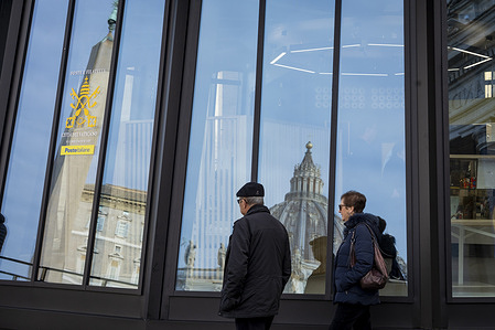 The Dome of St. Peter's Basilica is reflected in the windows of the new Vatican Post Office during the opening day for the Jubilee at St. Peter's Square in Vatican City. A new Post Office in Saint Peter’s Square is inaugurated on December 19 by Cardinal Fernando Vérgez Alzaga and executives from Poste Italiane. This new facility, donated by Poste Italiane, is meant to serve pilgrims and visitors during the Jubilee. It will be located on the left side of the Square, replacing the older Franzisella mobile post office that was installed in 2010.