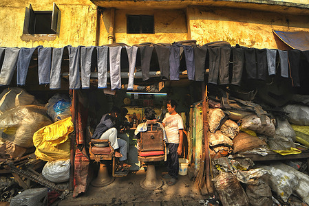Used pairs of jeans are seen hanging to dry before they are sold in a second-hand clothes market in front of a roadside barber shop. ‘Jeans gully’, as it's commonly known, is a distinctive area in Kolkata where cast-off, overlooked, and unsold jeans and dungarees from across the city converge, finding new purpose. Traders assert that the price for each pair is Rs 50-60 (1 - 2 USD) post-treatment, and it is sold in the state at twice that price. “Traders assert that the profit margin rises when they operate in various states.”