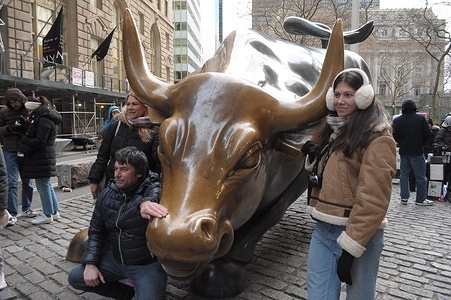 People take photos by the "Charging Bull" statue in the Financial District in Manhattan, New York City.