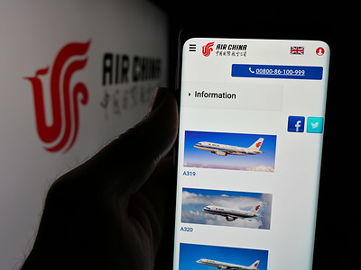 In this photo illustration, a person is holding a smartphone with the web page of Chinese airline company Air China Limited on screen in front of logo.