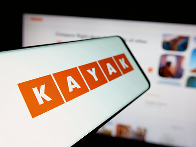 In this photo illustration, a smartphone with the logo of US travel metasearch company Kayak is seen on screen in front of website.