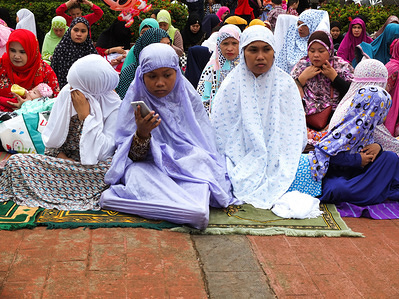 A Muslim woman using a smartphone during a prayer break.
Filipino and foreign Muslims gather at Quirino Grandstand in Manila to celebrate the end of Ramadan. They celebrate it with prayers, food and fun, especially for the family. Eid al-Fitr is an important religious holiday celebrated by Muslims worldwide that marks the end of Ramadan, the Islamic holy month of fasting.
