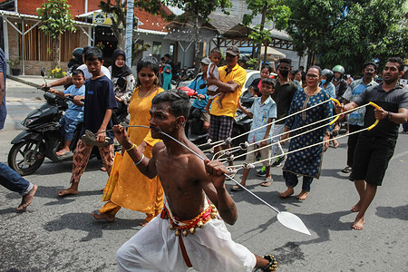 A Hindu man of the Tamil tribe participates in the cheek and body piercing ritual during the annual celebration in commemoration of the month of Pangguni or Pangguni Uthiram, which is in worship of the god Muruga.
