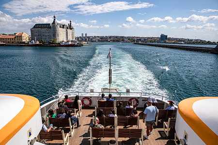 People enjoy the sea view on the terrace of the ferry departing from Kadikoy and Haydarpasa station in the background.