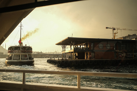 The steamboat leaves the pier with the steam coming out of the chimney.