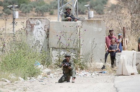 Israeli soldiers guard Jewish settlers during a demonstration at the Beit Furik checkpoint east of the West Bank city of Nablus. Dozens of Jewish settlers demonstrated at the Israeli checkpoints surrounding the areas of the Palestinian Authority headed by President Mahmoud Abbas, preventing Palestinians from moving within the PA territory.
