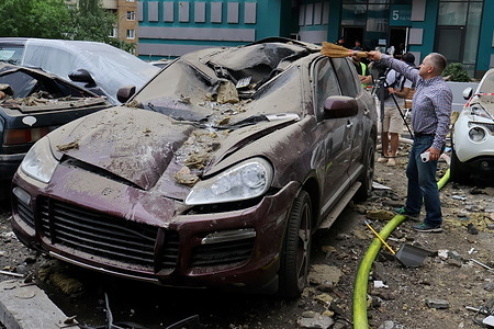 A local resident cleans his car at the site where an apartment building was damaged by Russian missile strikes in Kyiv. Destroyed apartments of a residential high-rise building hit by a Russian missile in Kyiv, Ukraine. On the night of May 24, Russia launched more than 20 missiles on the capital of Ukraine. A missile hitting a high-rise residential building resulted in the death of at least two persons and injuries to many residents.