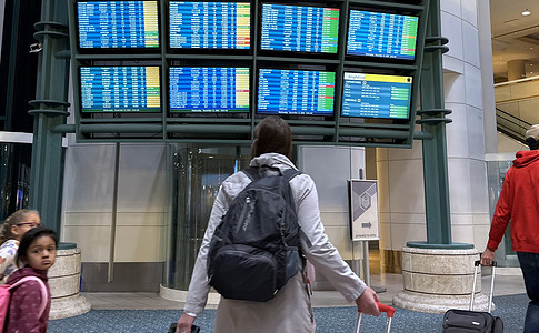 Air travelers view a flight status screen at Orlando International Airport on the 43rd day of the U.S. federal government shutdown. The Federal Aviation Administration has ordered reductions of up to 10 percent in operations at 40 major U.S. airports due to a shortage of air traffic controllers who are working without pay as the shutdown continues. Thousands of flight cancellations and delays have occurred since November 9. Congress is expected to vote as soon as tonight to end the shutdown.