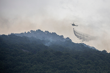 A firefighting helicopter drops water on a large wildfire in Boca de Huérgano. The cause of the fire was due to lightning, in an area of difficult access, with a perimeter of about 20 km. The fire has already burned more than 900 hectares.
