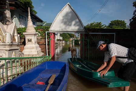 A man prepares a plastic boat during the floodwaters from the Chao Phraya River in front of his village in Ayutthaya. Ayutthaya flood was caused by heavy rainfall from tropical storms, which led to an increased discharge of water from the Chao Phraya Dam, overwhelming riverbanks in low-lying areas of the province.