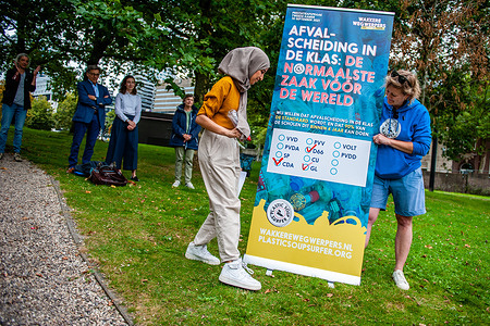Kauthar Bouchallikht (left), member of the House of Representatives of The Netherlands on behalf of the green political party GroenLinks is seen signing the campaign banner to draw attention to the separation of waste in educational institutions.
The biologist-turned-surfer Merijn Tinga, better known as Plastic Soup Surfer builds boards made out of plastic waste and uses them for expeditions that highlight global issues around plastic pollution. From the first of September until today he has been on his surfboard made from plastic waste, paddling around 300km, from Den Ham to The Hague, to draw attention to the separation of waste in educational institutions. After arriving at The Hague, he met with the secretaries of state and second members of the parliament.