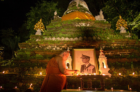 Thai Buddhist monk hold candle in front of the portrait of late Thai King Bhumibol Adulyadej during a religious ceremony to commemorate The 6th death anniversary of Thai King Bhumibol Adulyadej at Wat Pha Lat Temple. King Bhumibol died at the age of 88 in Siriraj hospital on 13 October 2016 after 70 years of reigning on the throne.