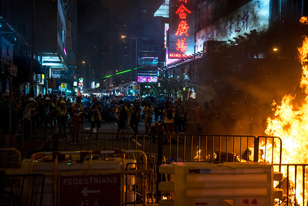 Protesters retreat from the Mong Kok police station after setting a street on fire during the demonstration
Protesters occupied streets outside of Prince Edward MTR station while also continuing to pay respects at one of the station exit. Riot police and police special forces were deployed to conduct dispersal operations.