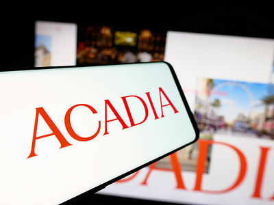 In this photo illustration, a smartphone with the logo of US real estate company Acadia Realty Trust is seen on screen in front of website.