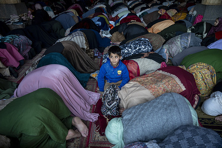 Kashmiri Muslim child looks on as women offer first Friday prayers of Ramadan at the historic Jamia Masjid or Grand Mosque in Downtown Srinagar. Ramadan is the ninth month of the Islamic lunar calendar, during which Muslims worldwide fast from dawn to sunset, refraining from food, drink and marital intimacy as a form of spiritual reflection, prayer and charity. Muslims believe the Quran was first revealed to the Prophet Muhammad during this month.