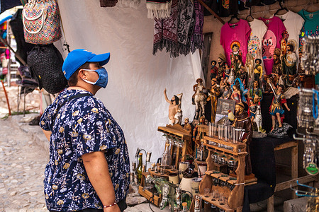 A tourist wearing a face mask as a preventive measure, looking at religious trinkets in a street shop.
Even though the number of visitors is not comparable with those before the Covid-19 pandemic, Real de Catorce in San Luis Potosí State has slowly began to restart the economy, especially where tourism is the main source of income.